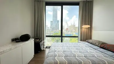 Modern bedroom with city view, large window, and stylish decor in urban apartment.
