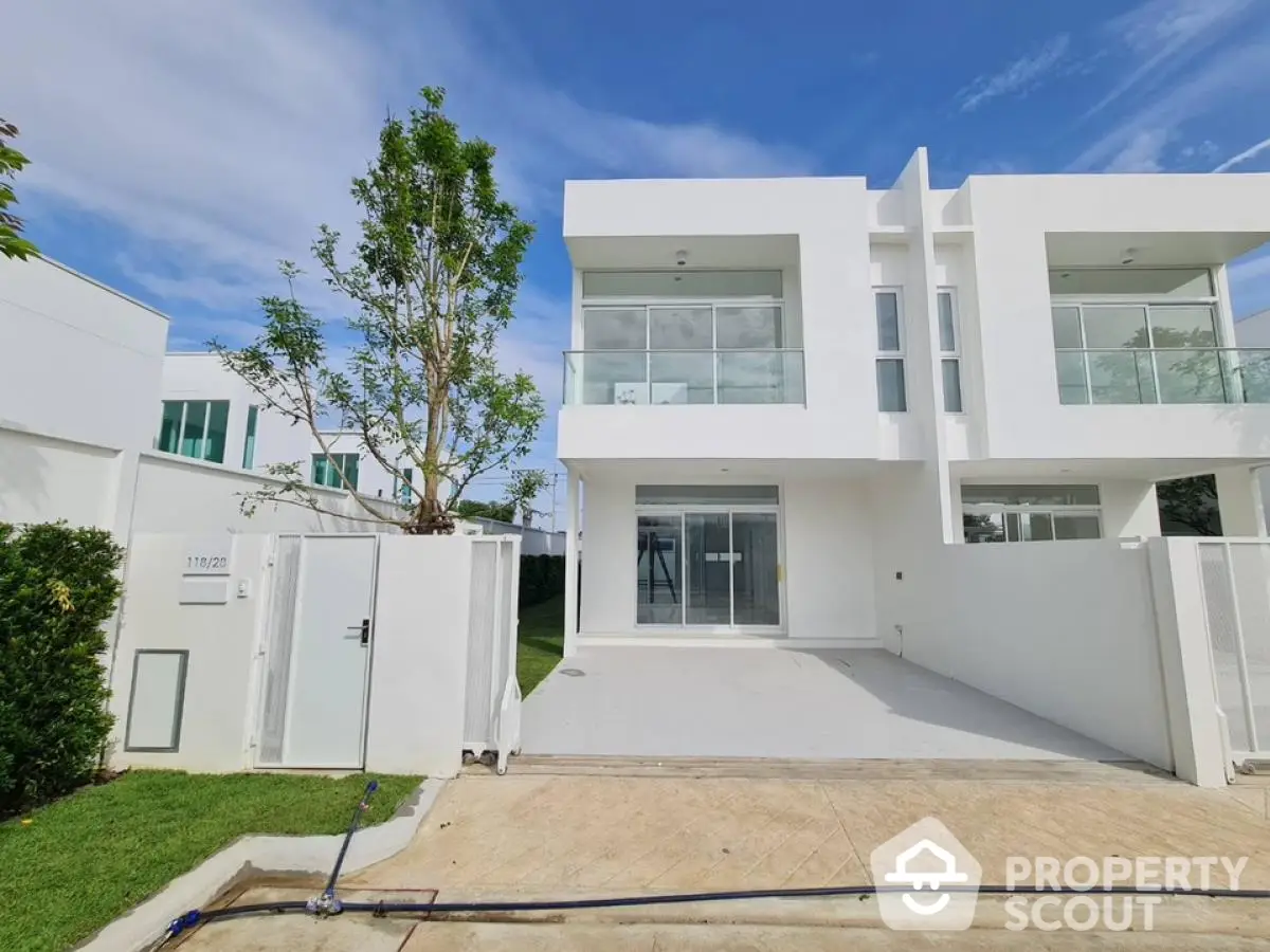 Modern white two-story house with spacious driveway and lush greenery