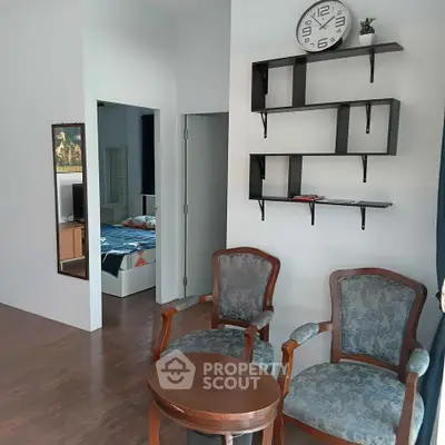 Charming living room with elegant chairs and modern wall shelves, perfect for cozy relaxation.