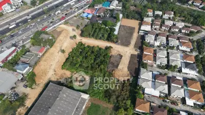 Aerial view of residential development with houses and green spaces near a highway.