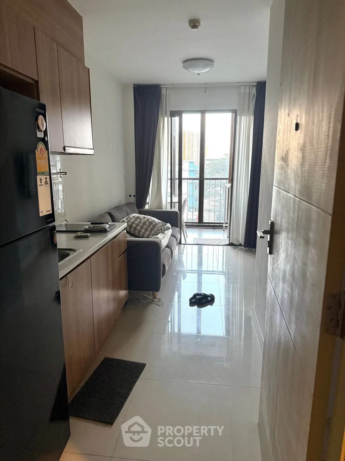 Modern apartment interior with open kitchen and cozy living area, featuring a balcony view.