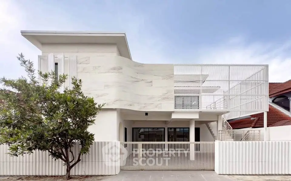 Modern minimalist white house exterior with unique architectural design and spacious outdoor area.