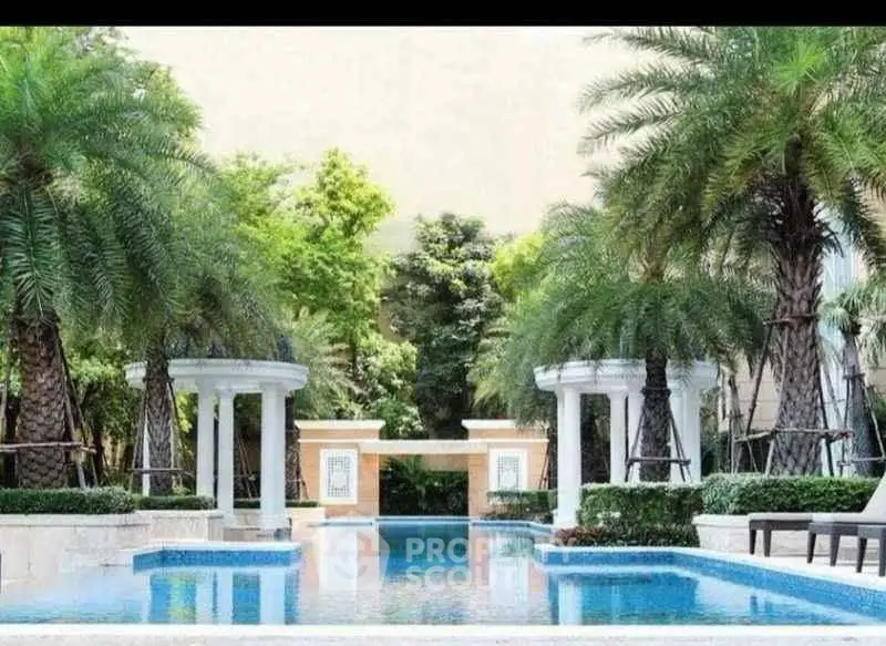 Luxurious pool area surrounded by lush greenery and elegant columns, perfect for relaxation and leisure.