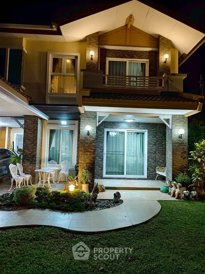Charming two-story house with elegant exterior lighting and cozy garden patio.