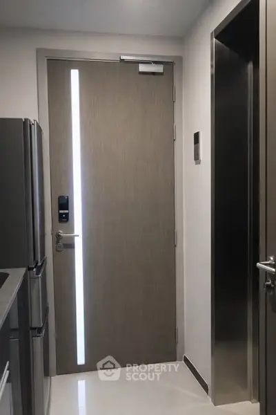 Modern apartment entrance with sleek door and stainless steel appliances.