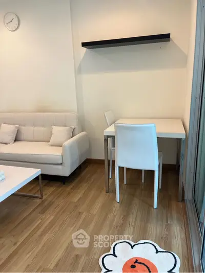 Modern living room with white sofa and dining table, wooden flooring, and minimalist decor.