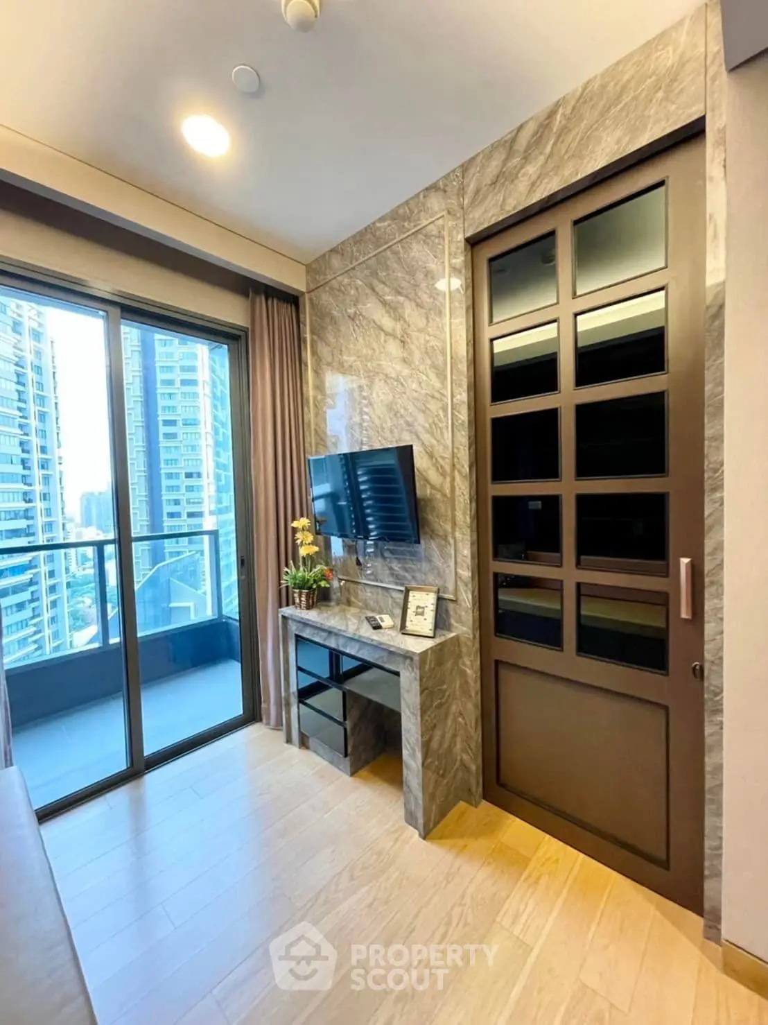 Modern living room with marble accents and balcony view in high-rise apartment.