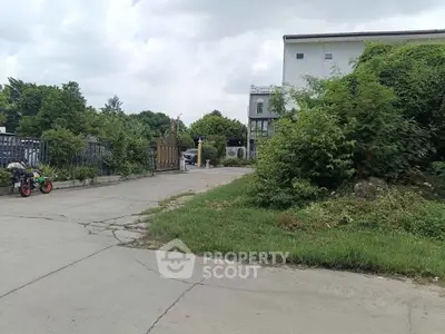 Spacious driveway leading to a residential building surrounded by lush greenery.