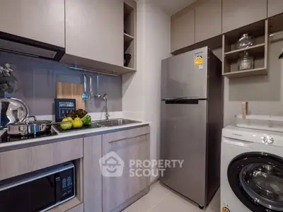 Modern kitchen with sleek appliances, washing machine, and stylish cabinetry in a compact layout.