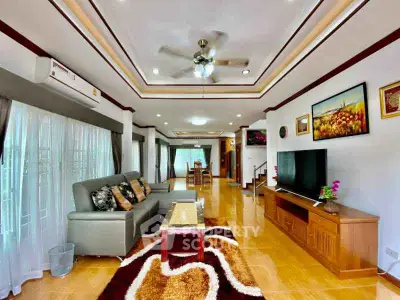 Spacious living room with modern decor and ceiling fan, featuring a cozy sofa and entertainment center.