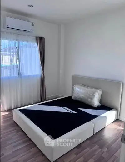 Modern bedroom with large window and air conditioning unit, featuring a stylish bed frame.