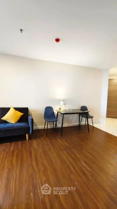 Modern living room with wooden flooring, cozy sofa, and dining area in a stylish apartment.