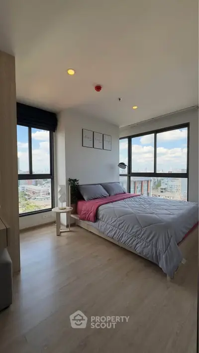 Modern bedroom with large windows offering city views and stylish decor.