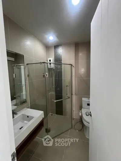 Modern bathroom with glass shower and sleek fixtures in contemporary apartment.