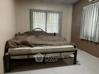 Cozy bedroom with simple decor and natural light from large windows.