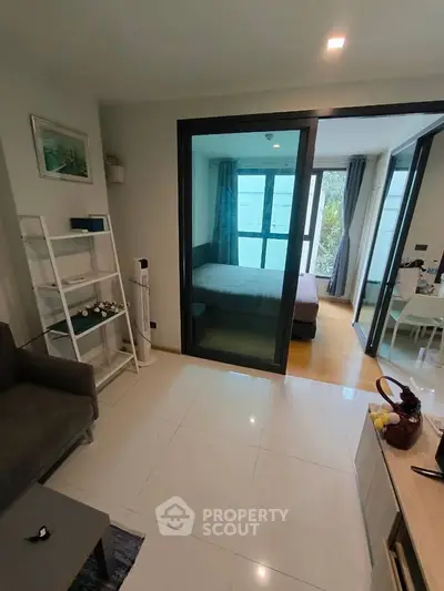 Modern apartment interior with glass partition, cozy living area, and bright bedroom.