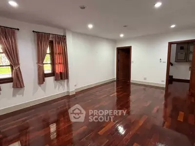 Spacious empty room with polished wooden floors and elegant curtains, perfect for customization.