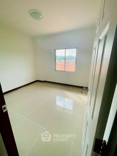 Spacious empty bedroom with glossy tiled floor and bright window view.