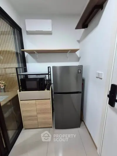 Modern kitchen corner with sleek fridge and microwave in compact layout.