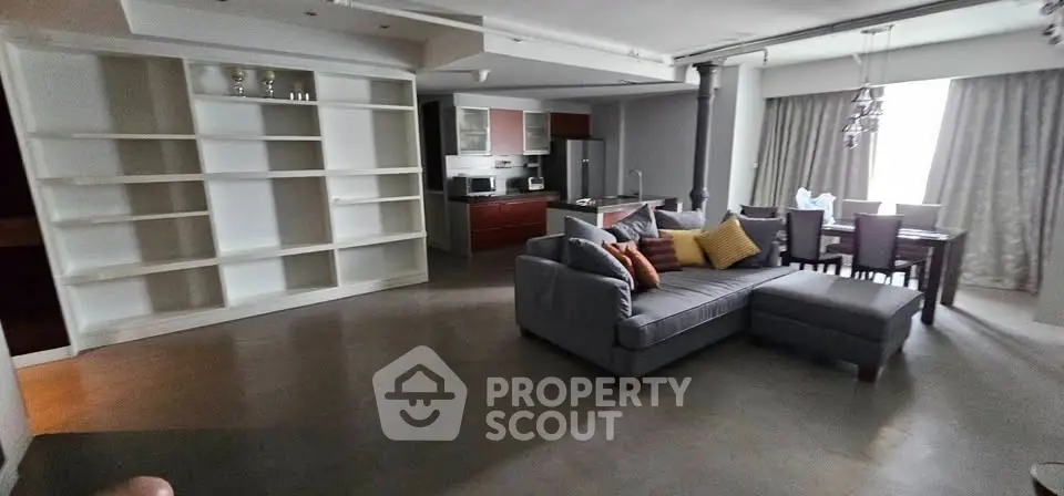 Spacious open-plan living room with modern kitchen and dining area, featuring a cozy sectional sofa and stylish decor.