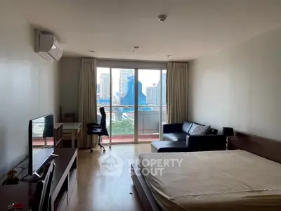Modern studio apartment with city view, featuring a cozy bed, sofa, and workspace.