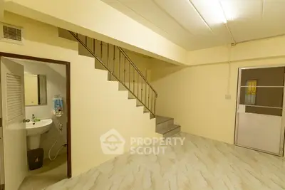 Spacious basement room with staircase and tiled flooring, ideal for storage or renovation.