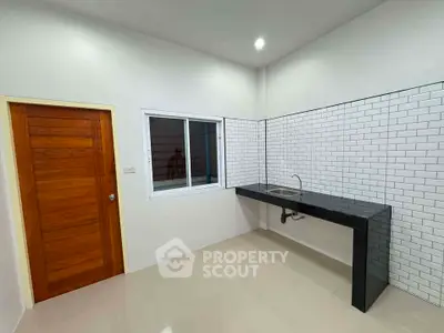 Modern minimalist kitchen with sleek black countertop and white subway tiles.