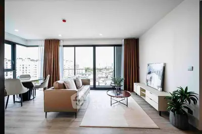 Spacious modern living room with large windows and stylish decor in a high-rise apartment.