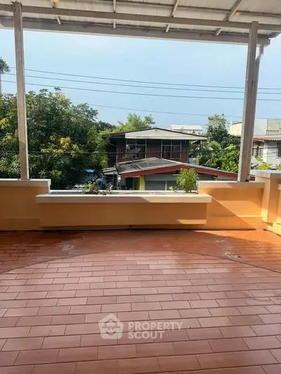 Spacious balcony with terracotta tiles and scenic neighborhood view.