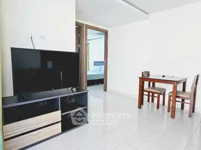 Modern living room with TV and dining area in a bright apartment.