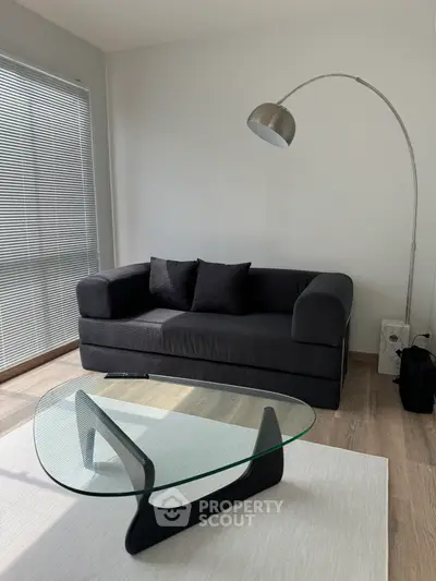 Modern living room with sleek black sofa and stylish glass coffee table, perfect for contemporary living.