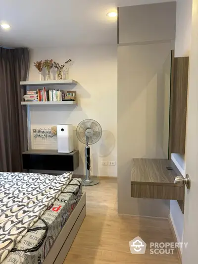 Modern bedroom with stylish decor and wooden flooring, featuring a cozy bed and elegant shelving.