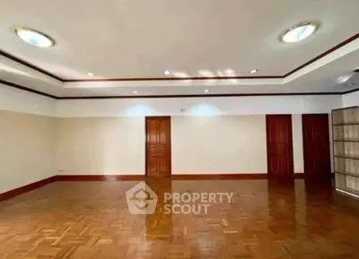 Spacious empty room with wooden flooring and recessed lighting, ideal for customization.