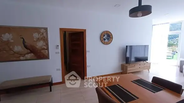 Modern living room with stylish decor and natural light, featuring a wall-mounted TV and elegant furniture.