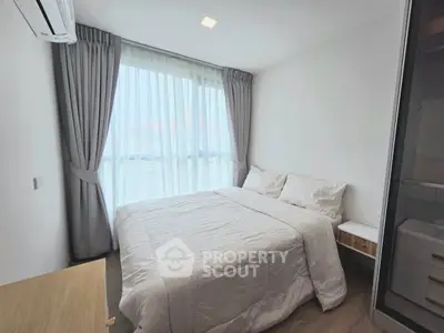 Cozy bedroom with large window and modern decor in a bright apartment.