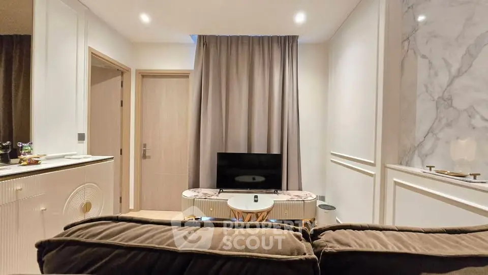 Modern living room with elegant decor and cozy seating area, featuring a sleek TV setup and stylish curtains.