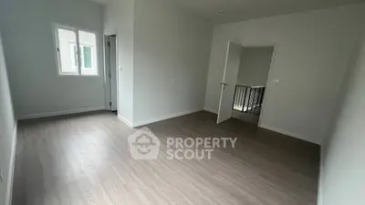 Spacious empty room with wooden flooring and natural light, ideal for customization.