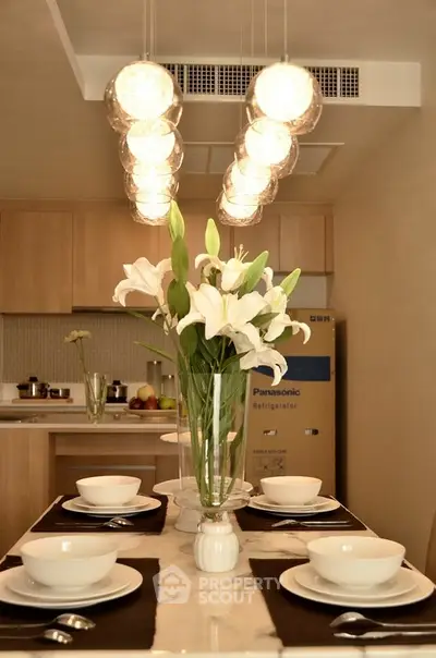 Elegant dining area with modern lighting and stylish kitchen in background, perfect for contemporary living.