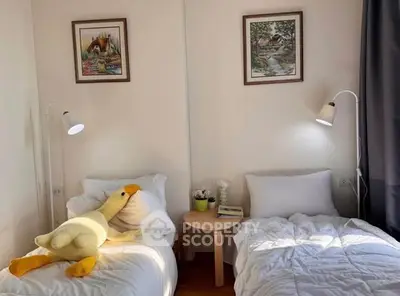 Cozy bedroom with twin beds, plush toy, and stylish decor, perfect for a comfortable stay.