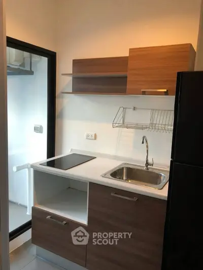 Modern compact kitchen with sleek cabinetry and electric cooktop in a cozy apartment.