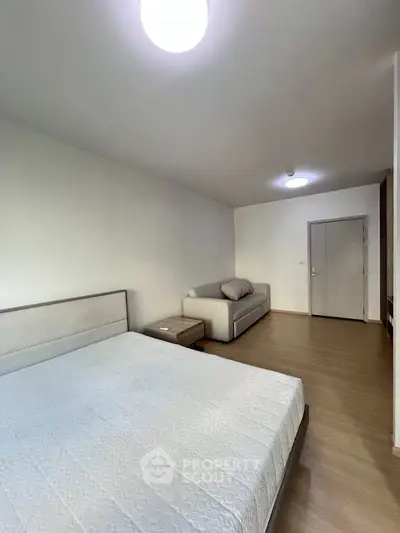 Spacious bedroom with modern decor and cozy seating area, perfect for relaxation and comfort.