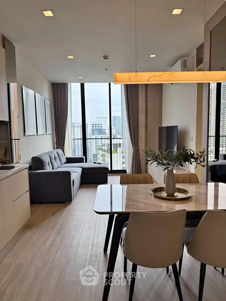 Modern living room with city view, stylish furniture, and elegant dining area in high-rise apartment.