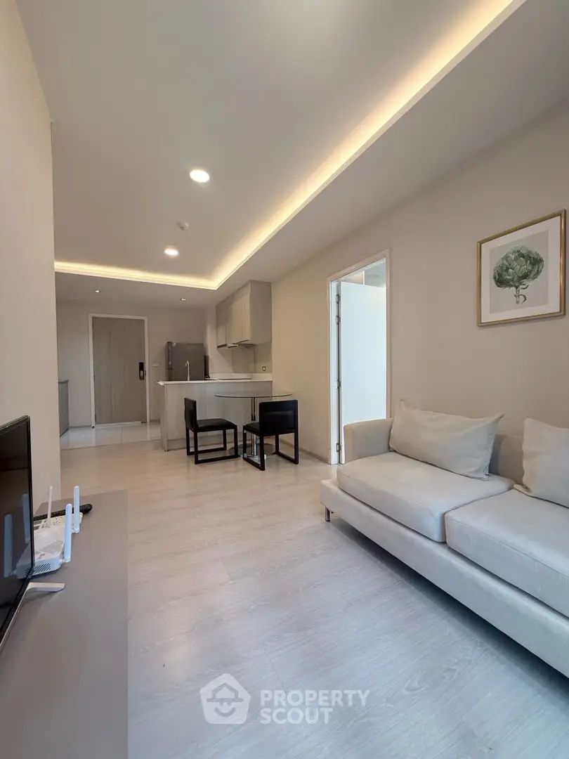 Modern living room with open kitchen, sleek furniture, and elegant lighting in a contemporary apartment.