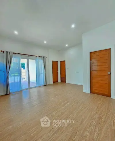 Spacious living room with wooden flooring and large windows for natural light.