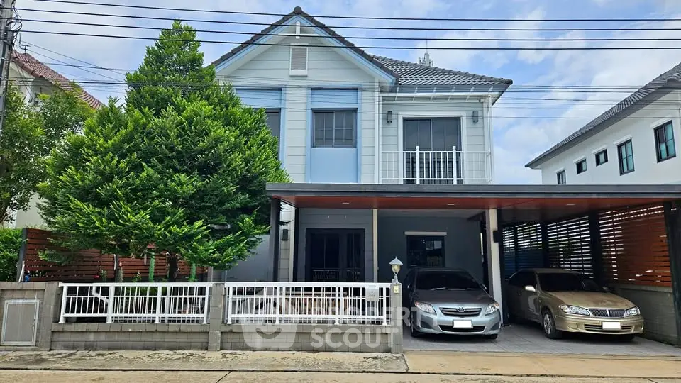 Charming two-story house with spacious carport and lush greenery in a serene neighborhood.