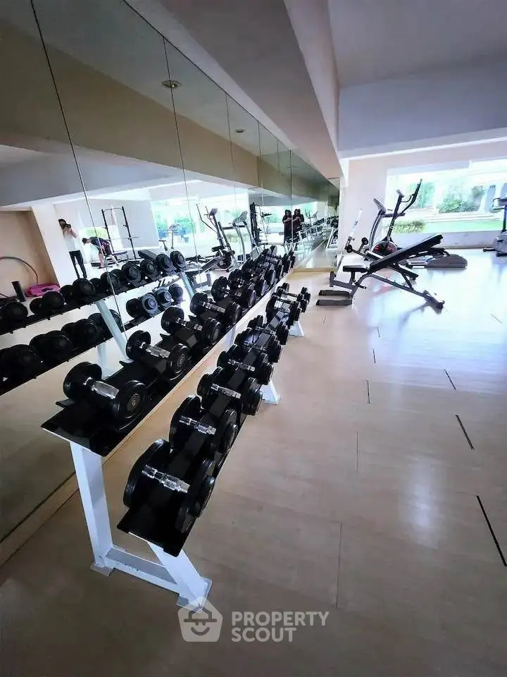 Spacious gym with modern equipment and mirrored walls in a residential complex.