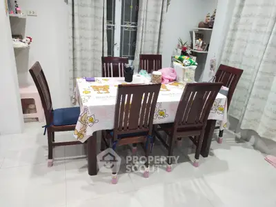 Charming dining area with wooden table and chairs, featuring playful tablecloth and bright decor accents.