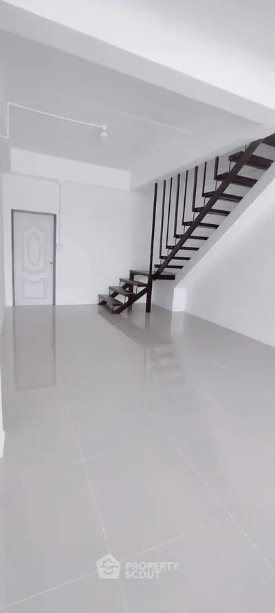 Modern minimalist interior with sleek staircase and glossy tiled floor, perfect for contemporary living.