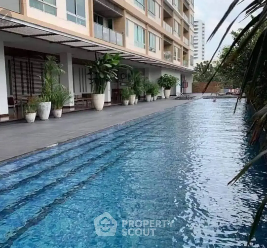 Luxurious apartment building with stunning poolside view and lush greenery.