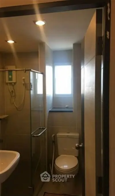 Compact modern bathroom with glass shower and natural light